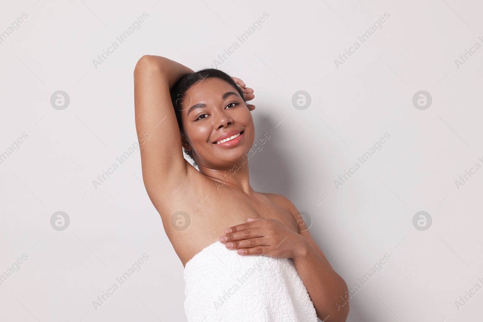 Woman showing hairless armpit after epilation procedure on light grey background Photo of Woman showing hairless armpit after epilation procedure on light grey background