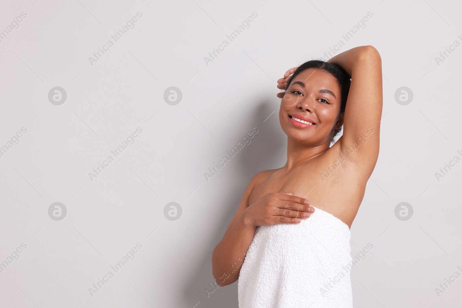 Woman showing hairless armpit after epilation procedure on light grey background, space for text Photo of Woman showing hairless armpit after epilation procedure on light grey background, space for text