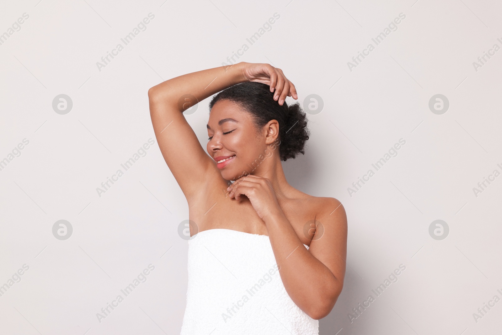 Woman showing hairless armpit after epilation procedure on light grey background Photo of Woman showing hairless armpit after epilation procedure on light grey background