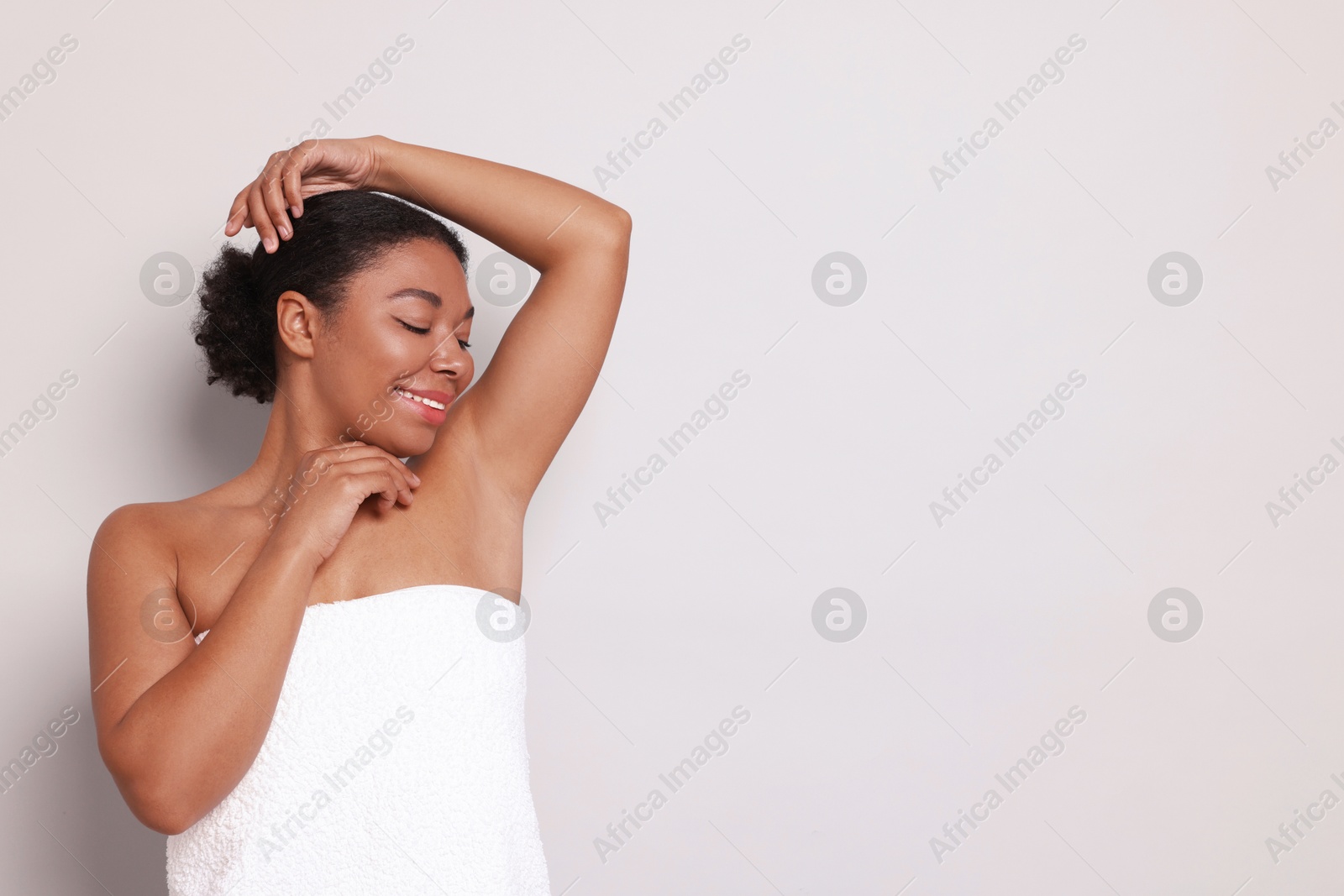 Woman showing hairless armpit after epilation procedure on light grey background, space for text Photo of Woman showing hairless armpit after epilation procedure on light grey background, space for text