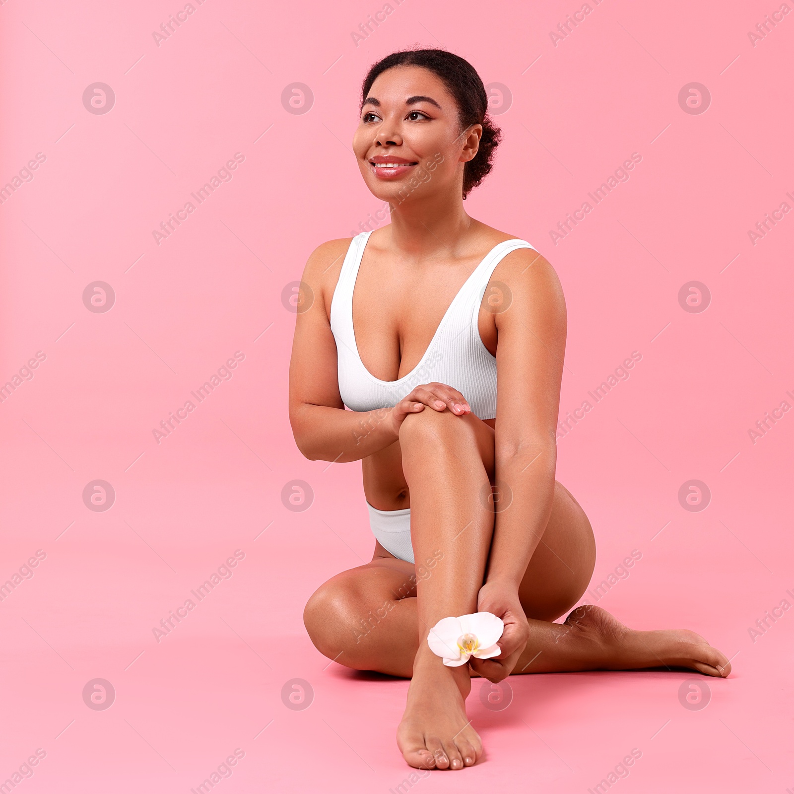Woman in underwear with flower showing smooth skin after epilation procedure on pink background, space for text Photo of Woman in underwear with flower showing smooth skin after epilation procedure on pink background, space for text