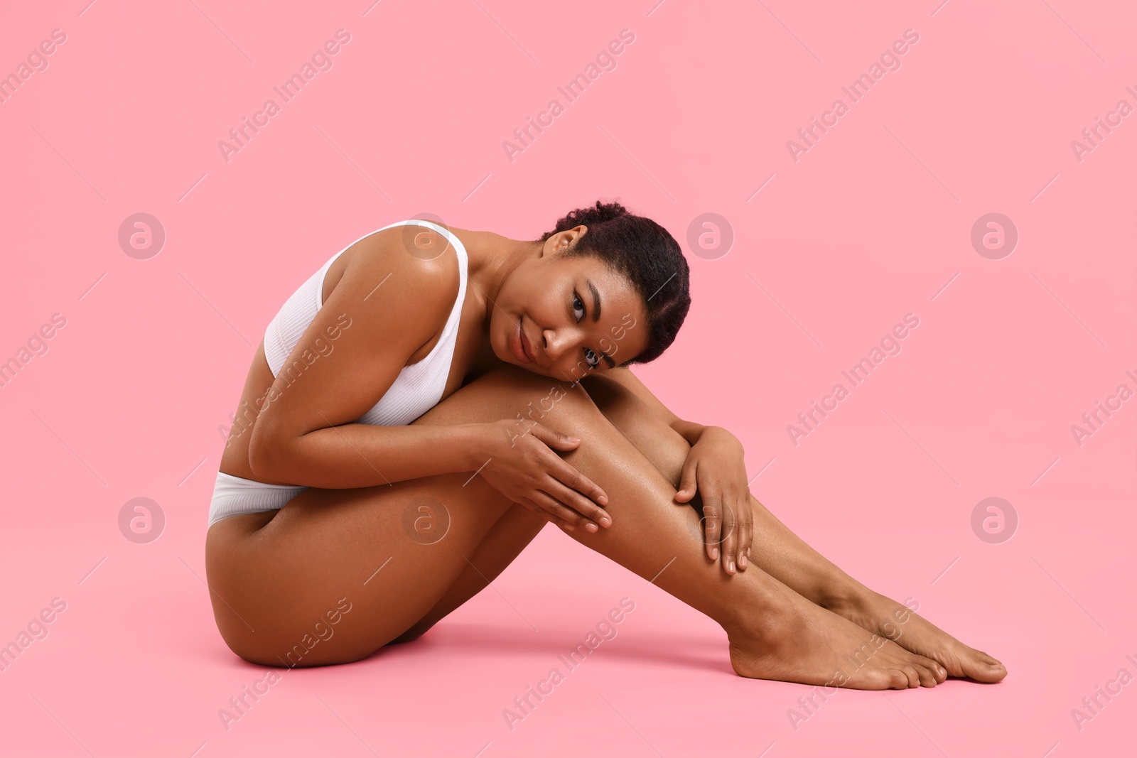 Woman in white underwear with smooth skin after epilation procedure on pink background Photo of Woman in white underwear with smooth skin after epilation procedure on pink background