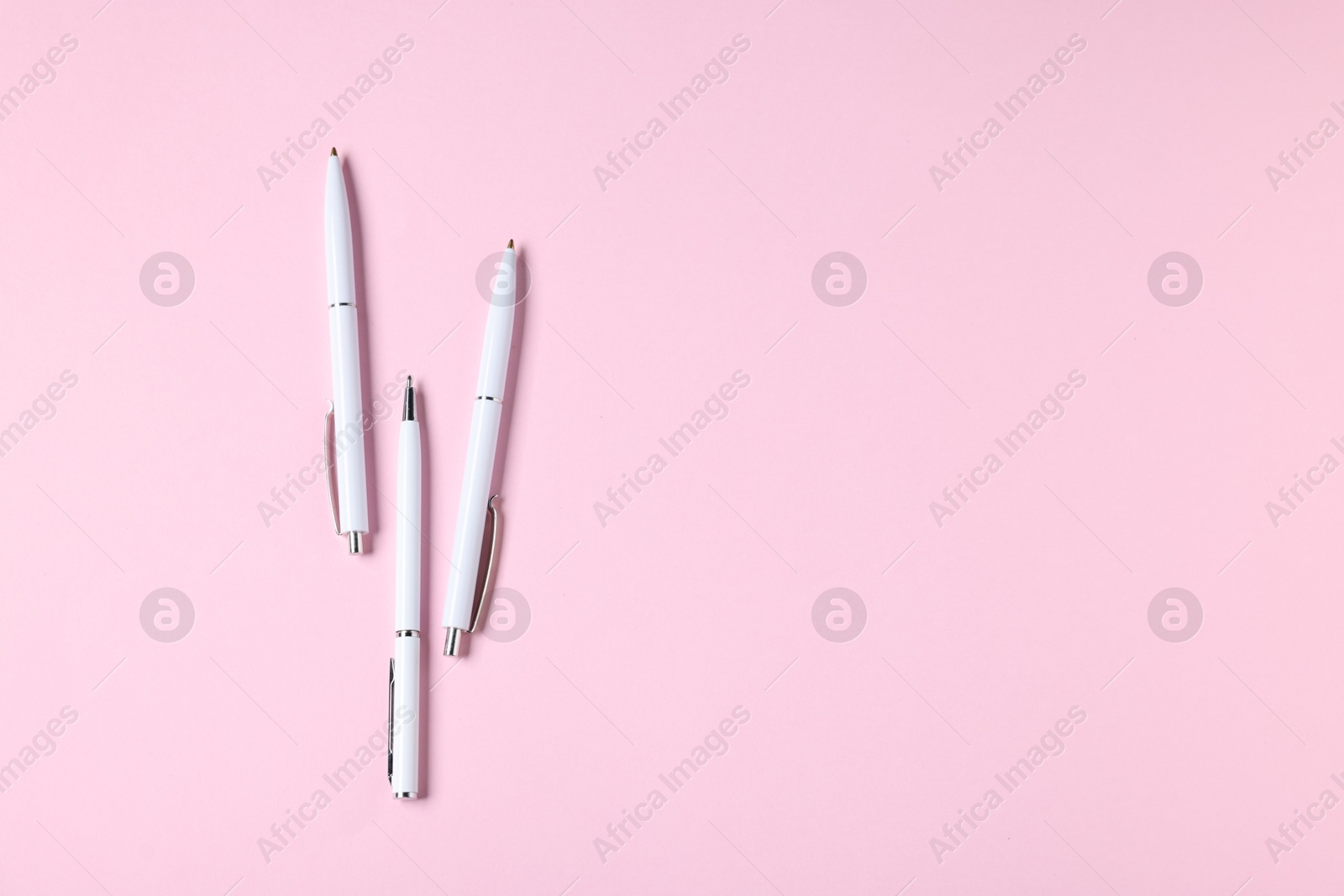 Ballpoint pens on pink background, flat lay. Space for text Photo of Ballpoint pens on pink background, flat lay. Space for text