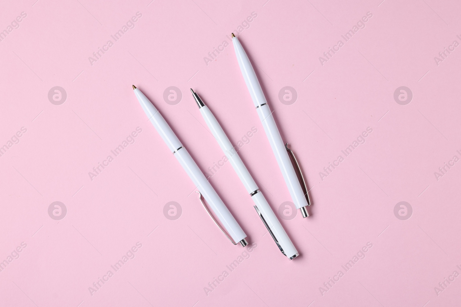 Ballpoint pens on pink background, flat lay Photo of Ballpoint pens on pink background, flat lay