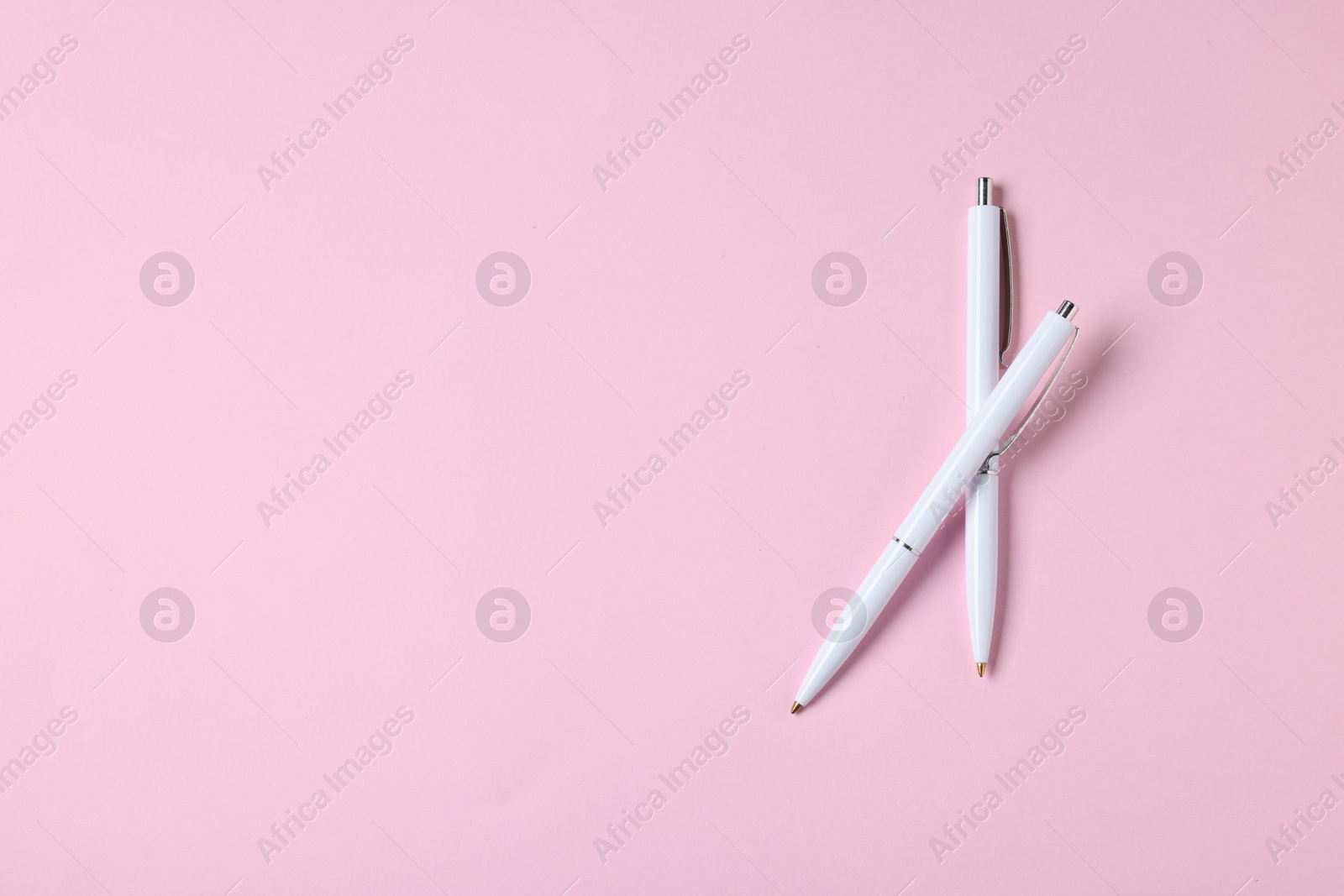 Ballpoint pens on pink background, top view. Space for text Photo of Ballpoint pens on pink background, top view. Space for text