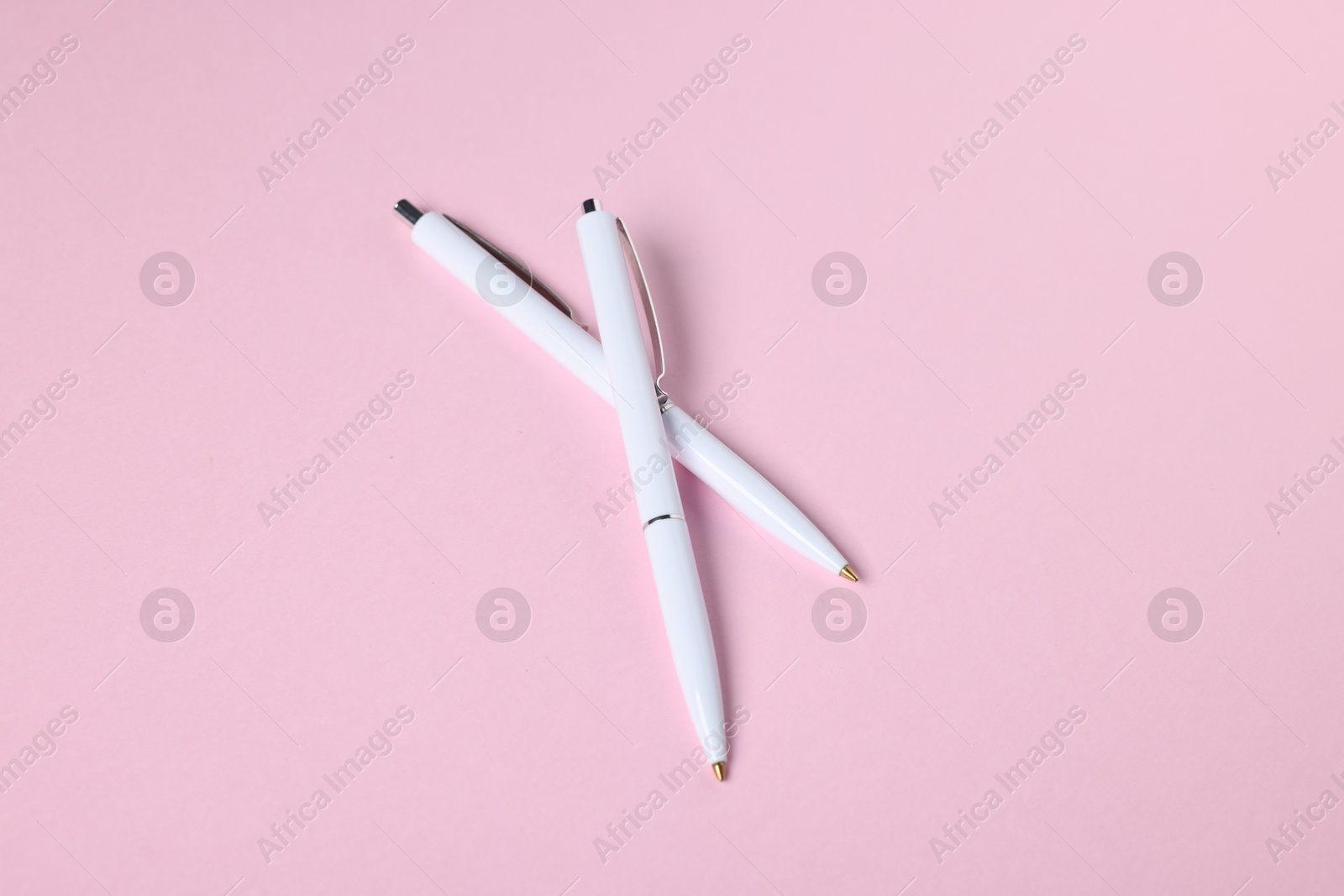 Ballpoint pens on pink background, above view Photo of Ballpoint pens on pink background, above view