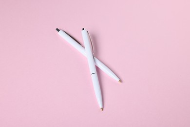 Photo of Ballpoint pens on pink background, above view