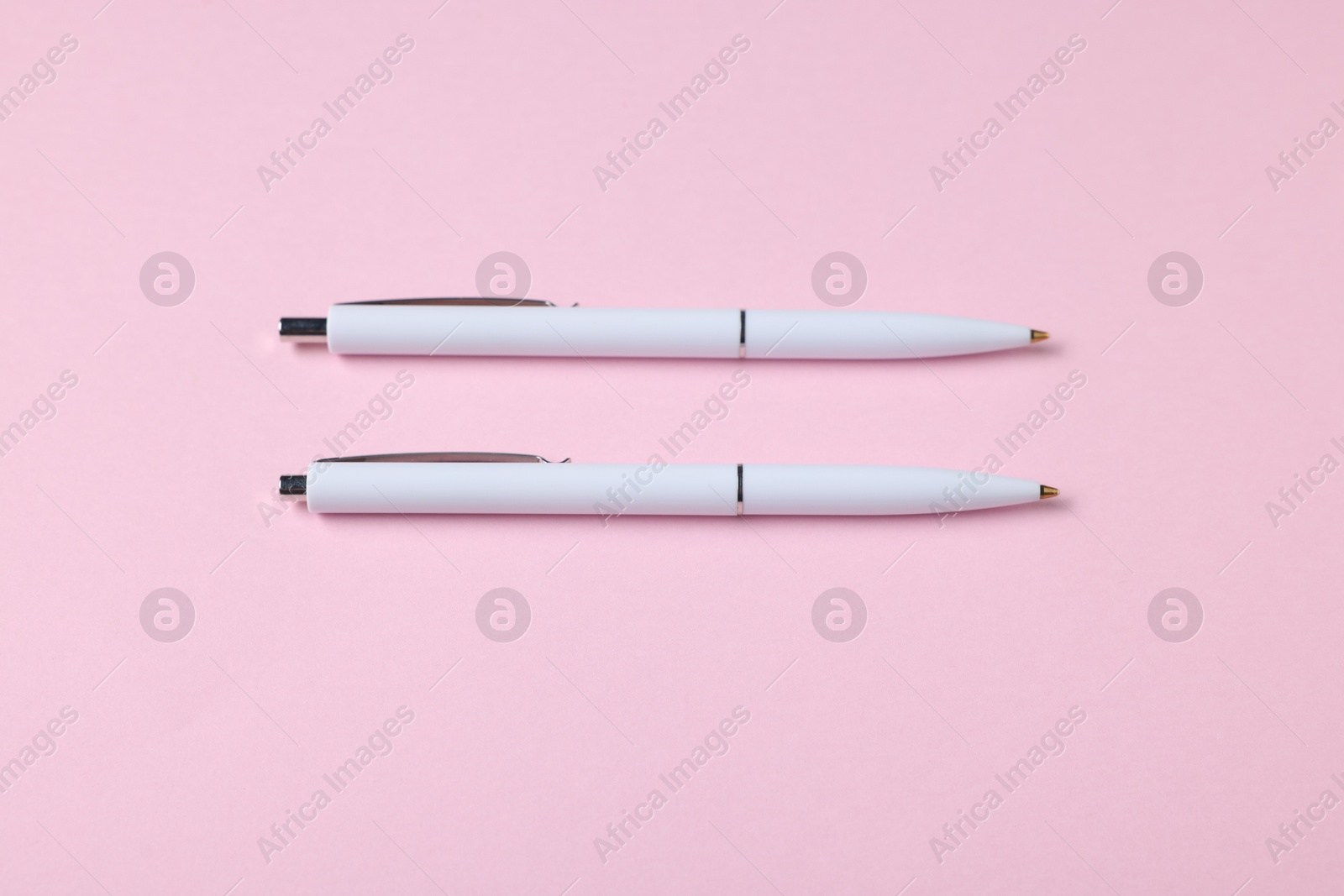 Ballpoint pens on pink background, flat lay Photo of Ballpoint pens on pink background, flat lay