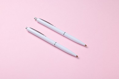 Photo of Ballpoint pens on pink background, above view
