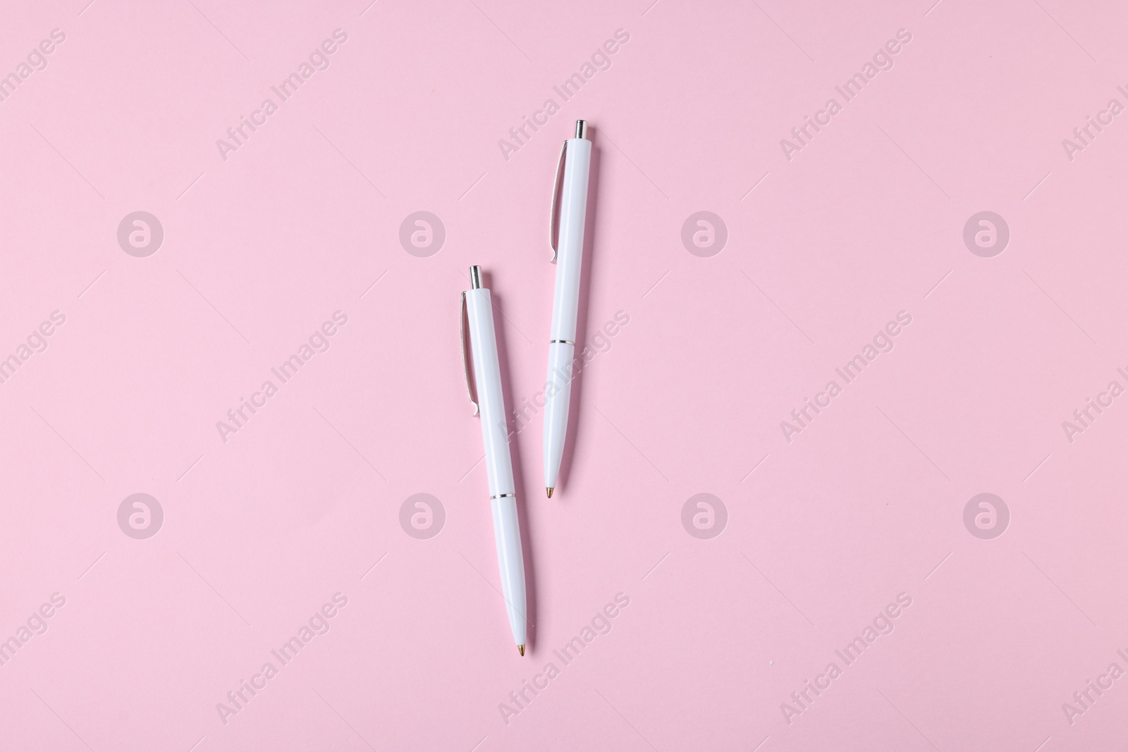Ballpoint pens on pink background, flat lay Photo of Ballpoint pens on pink background, flat lay