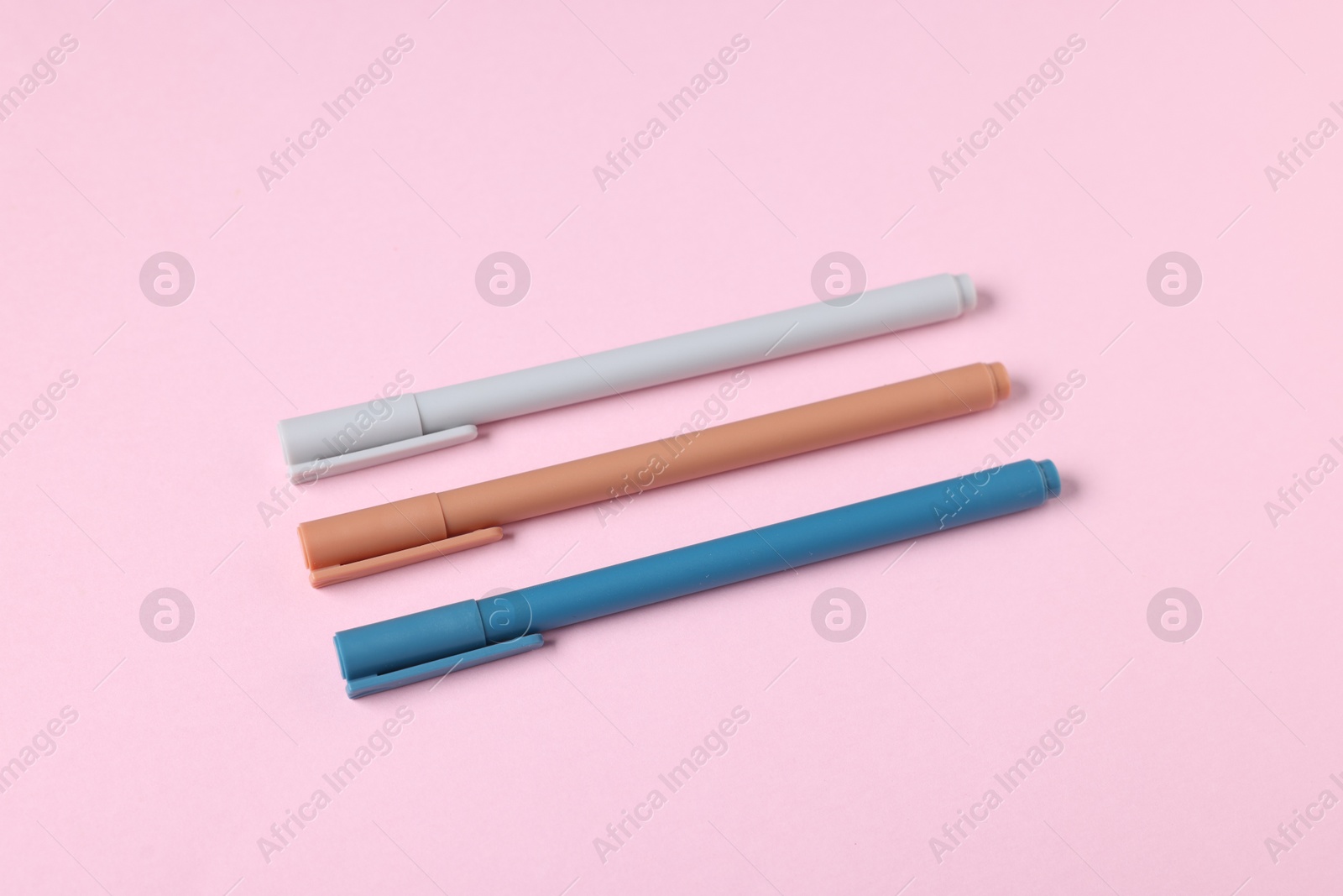 Stylish pens on pink background, above view Photo of Stylish pens on pink background, above view