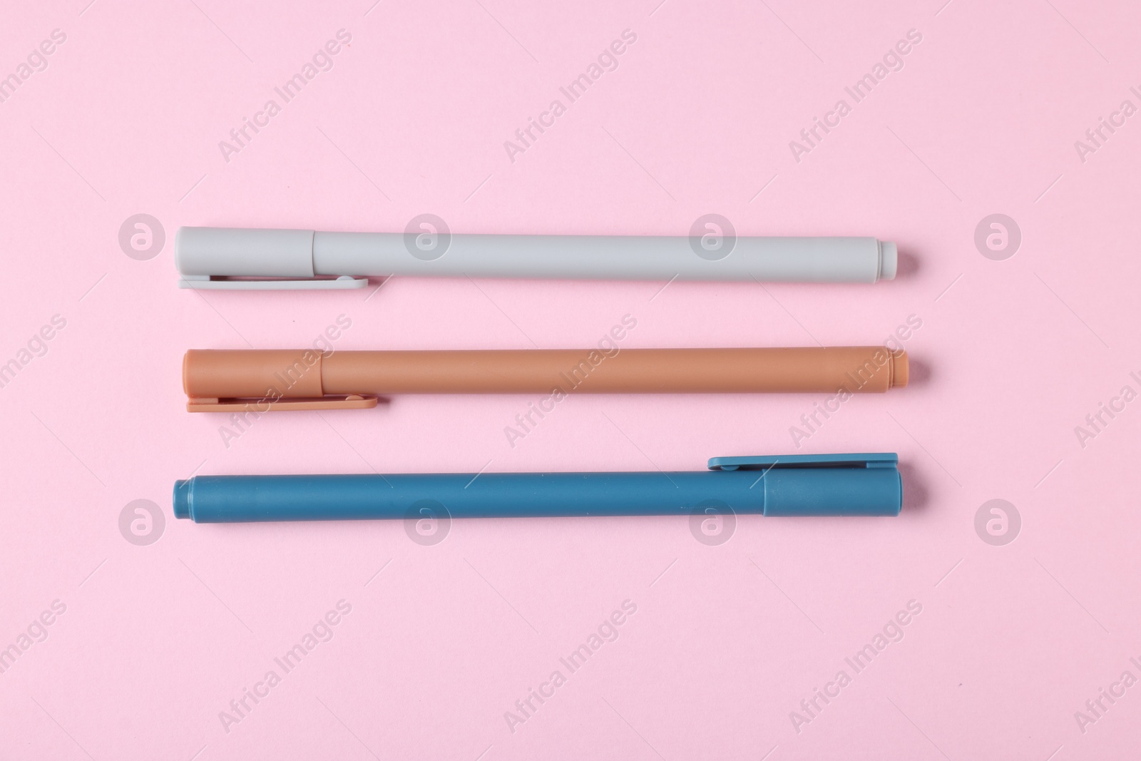 Stylish pens on pink background, flat lay Photo of Stylish pens on pink background, flat lay