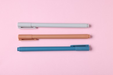 Photo of Stylish pens on pink background, flat lay