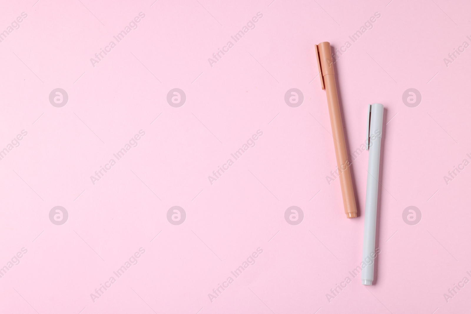 Stylish pens on pink background, top view. Space for text Photo of Stylish pens on pink background, top view. Space for text