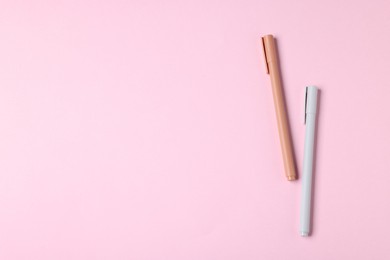 Photo of Stylish pens on pink background, top view. Space for text