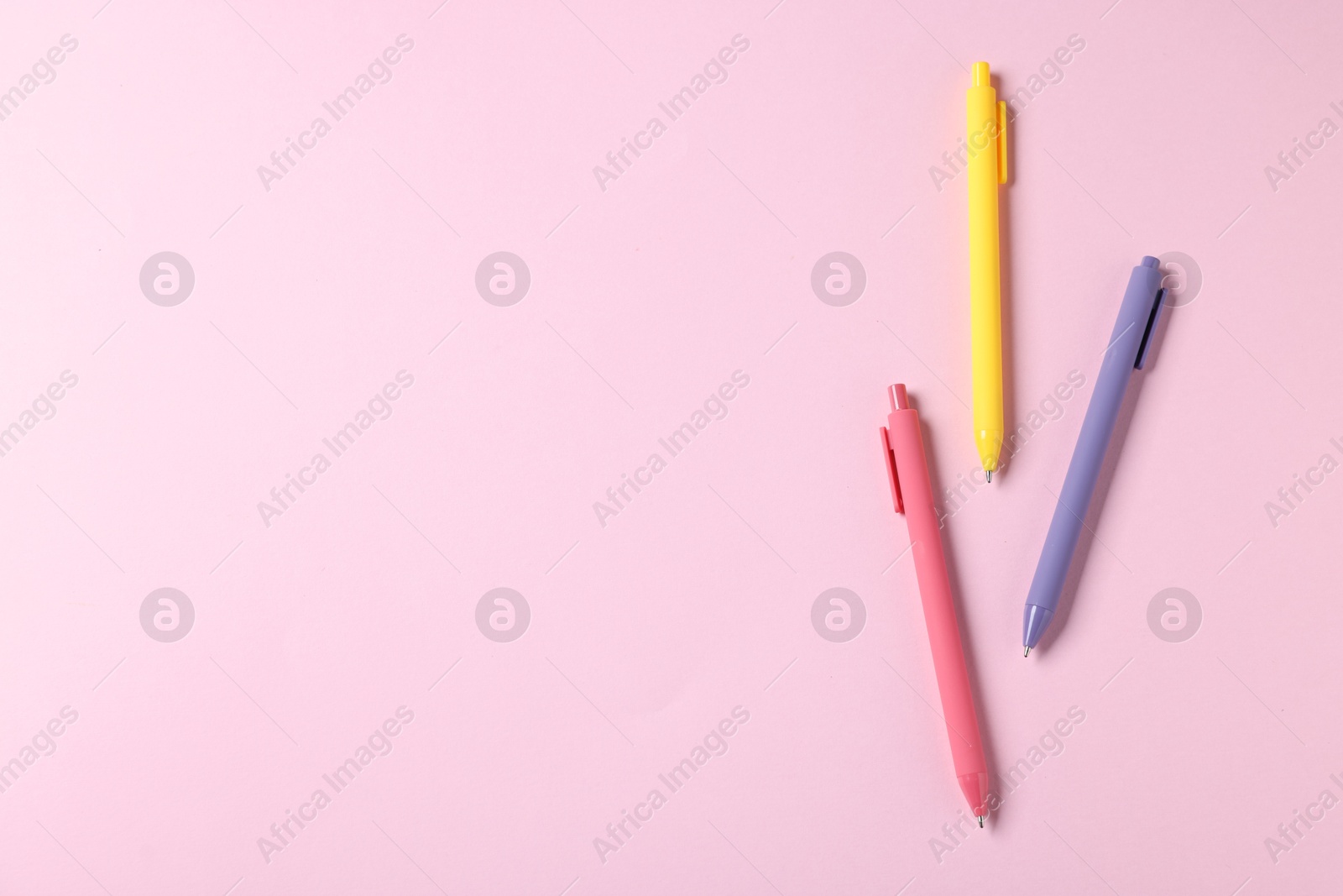 Set of ballpoint pens on pink background, flat lay. Space for text Photo of Set of ballpoint pens on pink background, flat lay. Space for text