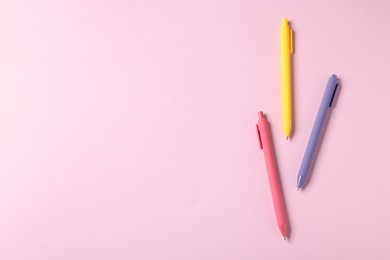 Photo of Set of ballpoint pens on pink background, flat lay. Space for text