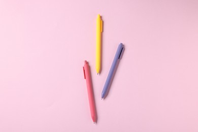 Photo of Set of ballpoint pens on pink background, flat lay