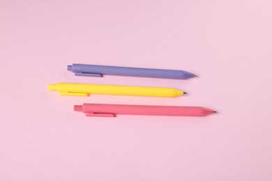 Photo of Set of ballpoint pens on pink background, flat lay