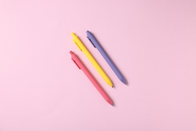 Photo of Set of ballpoint pens on pink background, flat lay