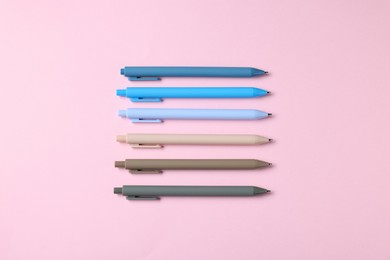 Photo of Set of ballpoint pens on pink background, flat lay
