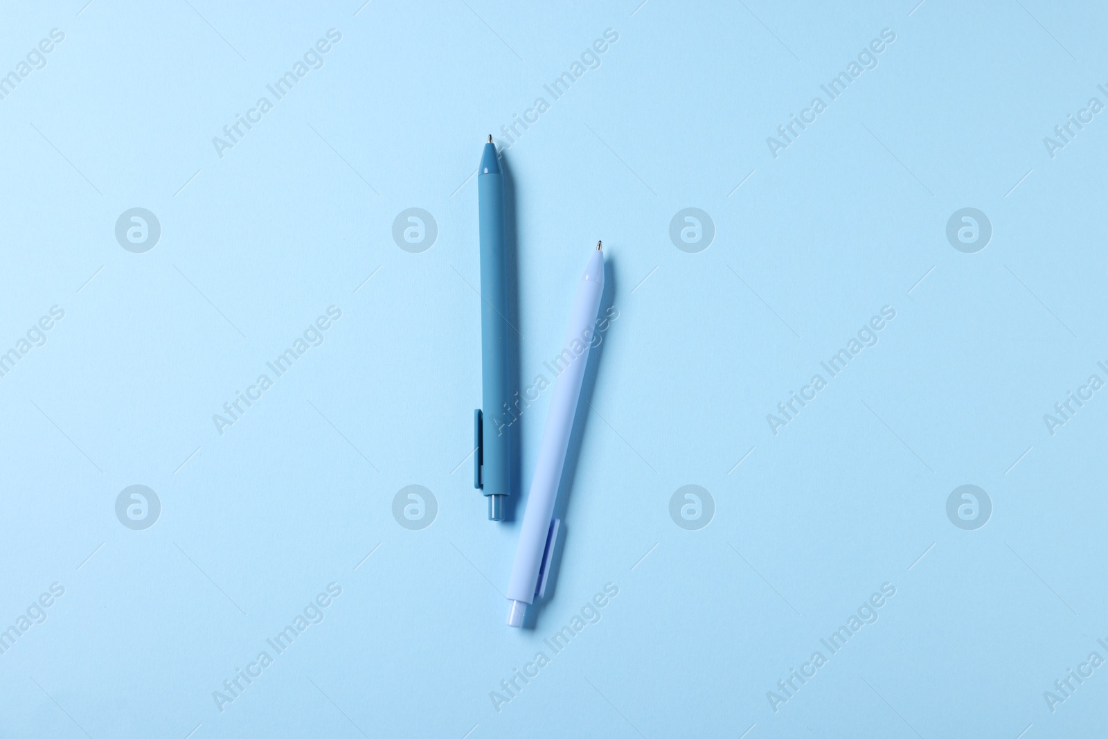 Stylish pens on light blue background, top view Photo of Stylish pens on light blue background, top view