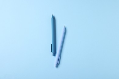 Photo of Stylish pens on light blue background, top view