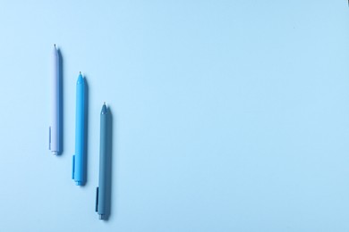 Photo of Stylish pens on light blue background, flat lay. Space for text