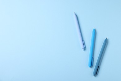 Photo of Stylish pens on light blue background, flat lay. Space for text
