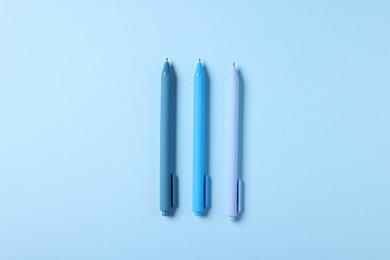 Photo of Stylish pens on light blue background, flat lay