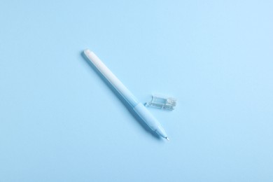 Photo of One stylish pen and lid on light blue background, top view