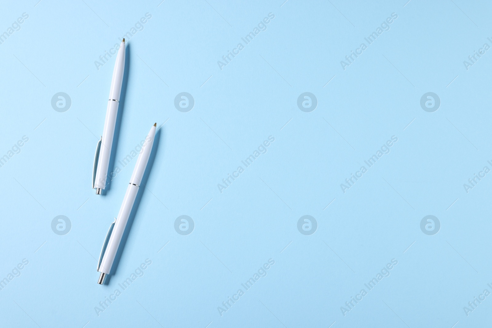 Stylish pens on light blue background, top view. Space for text Photo of Stylish pens on light blue background, top view. Space for text