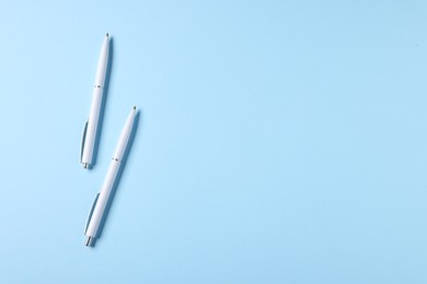 Photo of Stylish pens on light blue background, top view. Space for text