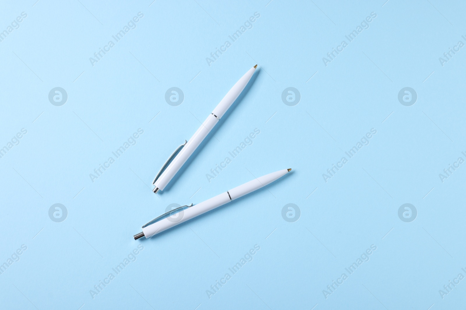 Stylish pens on light blue background, top view Photo of Stylish pens on light blue background, top view