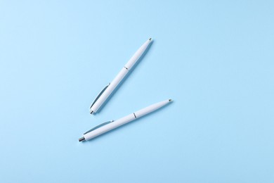 Photo of Stylish pens on light blue background, top view