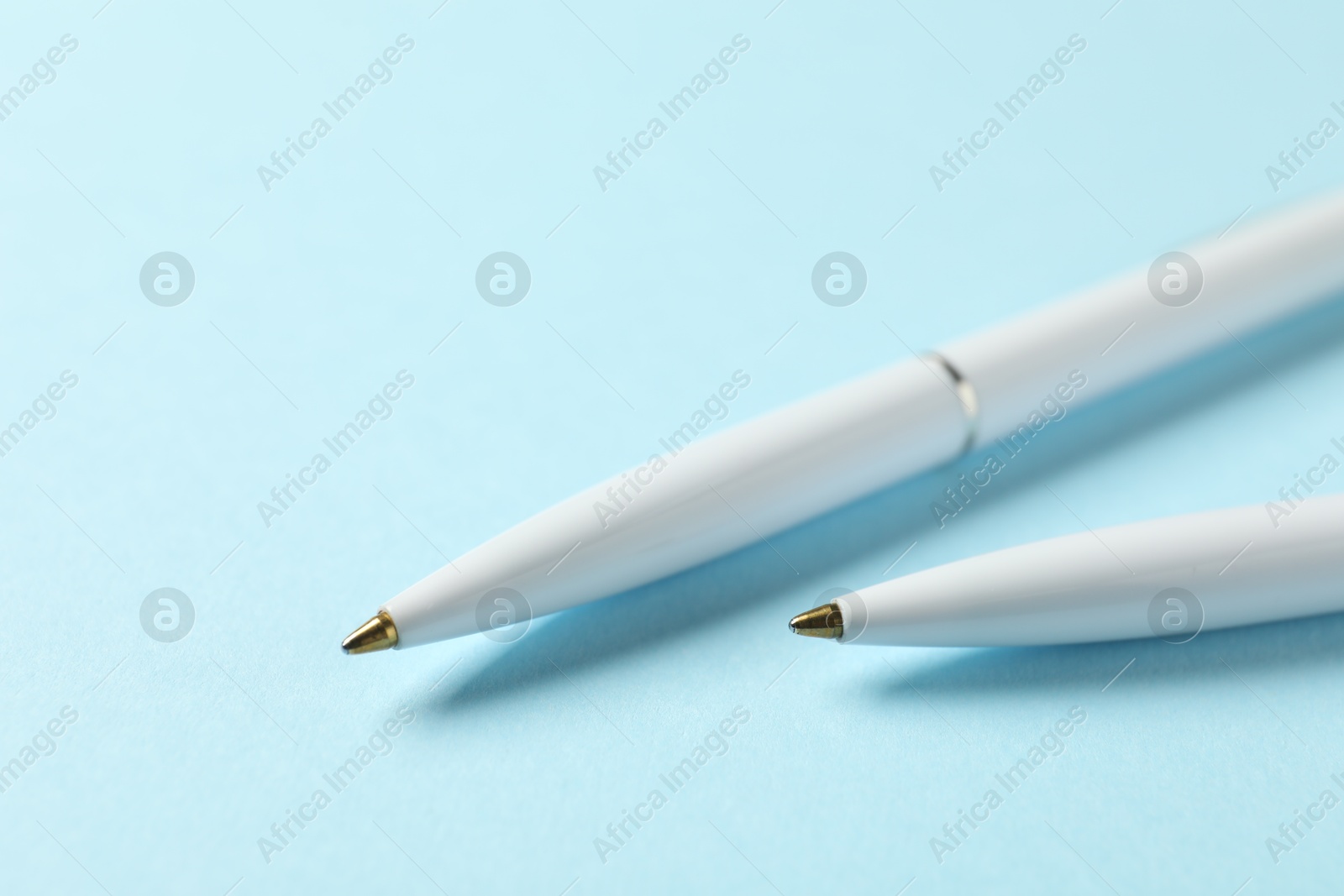Stylish pens on light blue background, closeup Photo of Stylish pens on light blue background, closeup