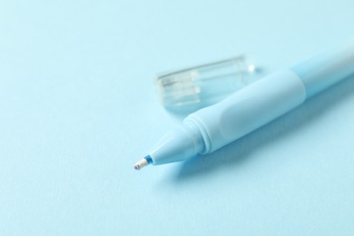 Photo of One stylish pen and lid on light blue background, closeup. Space for text