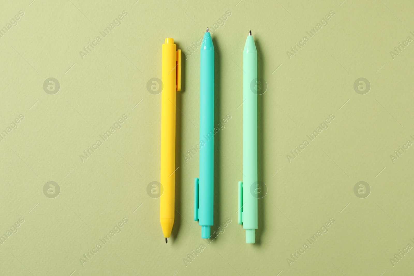 Stylish pens on green background, flat lay Photo of Stylish pens on green background, flat lay