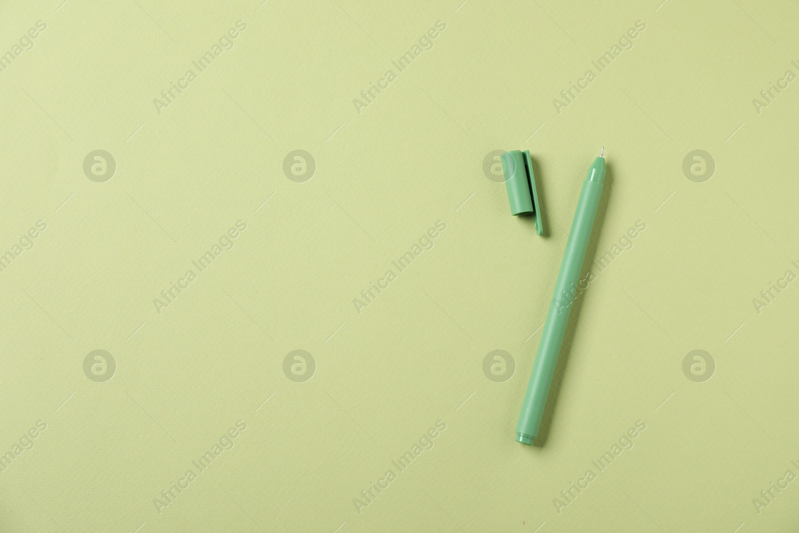 One stylish pen and lid on green background, top view. Space for text Photo of One stylish pen and lid on green background, top view. Space for text