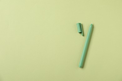 Photo of One stylish pen and lid on green background, top view. Space for text