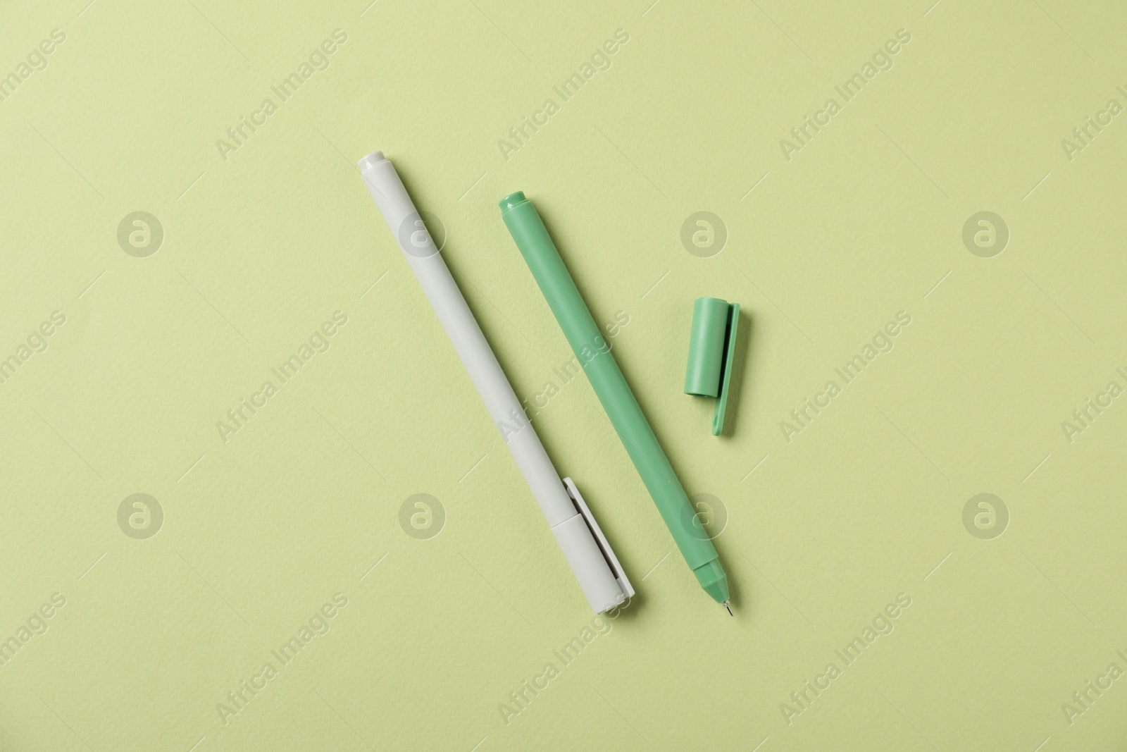 Stylish pens on green background, flat lay Photo of Stylish pens on green background, flat lay