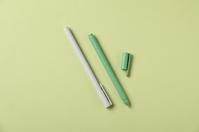Photo of Stylish pens on green background, flat lay