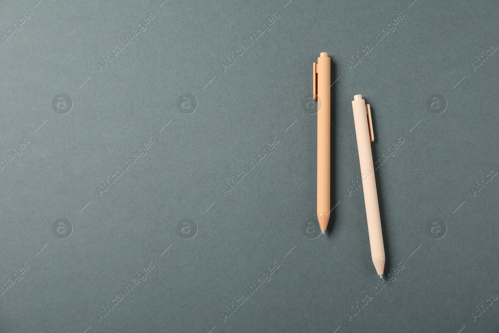 Stylish pens on grey background, above view. Space for text Photo of Stylish pens on grey background, above view. Space for text
