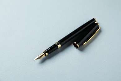 Photo of One stylish fountain pen and lid on grey background