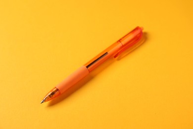 Photo of One stylish pen on orange background, closeup