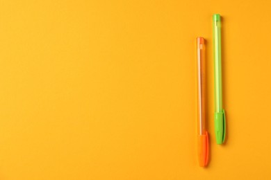 Photo of Stylish pens on orange background, top view. Space for text