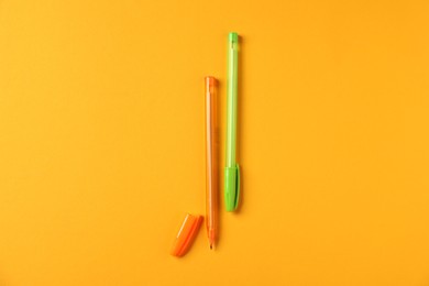 Photo of Stylish pens on orange background, flat lay
