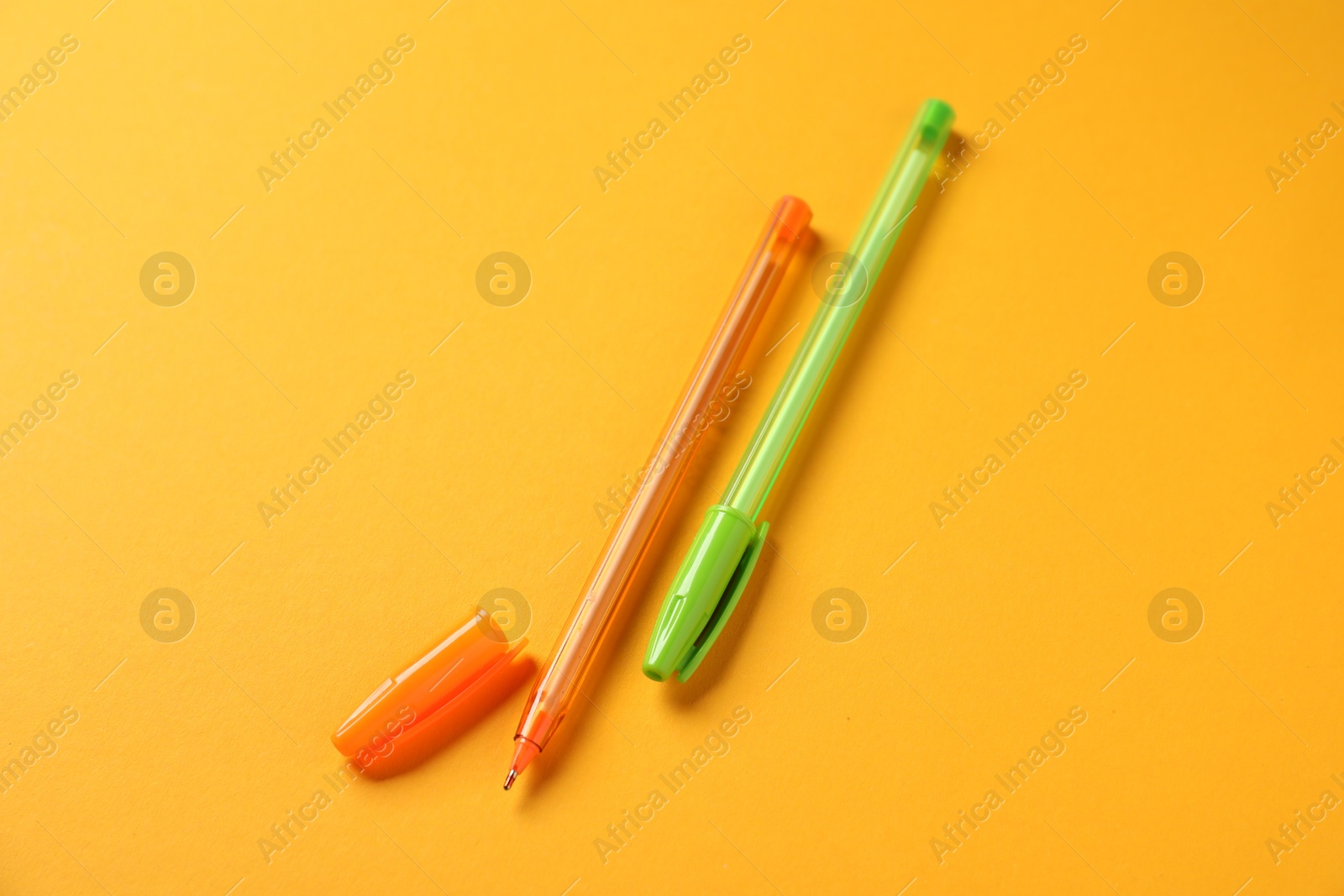 Stylish pens on orange background, above view Photo of Stylish pens on orange background, above view