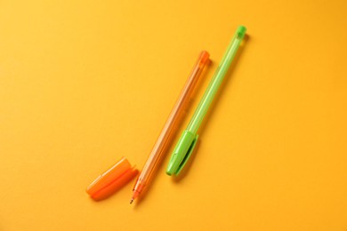 Photo of Stylish pens on orange background, above view