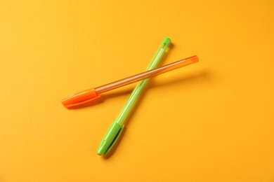 Photo of Stylish pens on orange background, above view